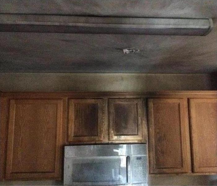 Burned kitchen, cabinet and ceiling covered with soot 
